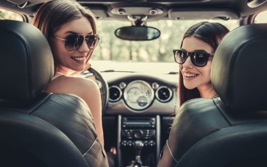 Women in car smiling and looking into the back seat